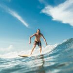 shirtless male surfer riding waves in ocean at Nusa Dua Beach, Bali, Indonesia